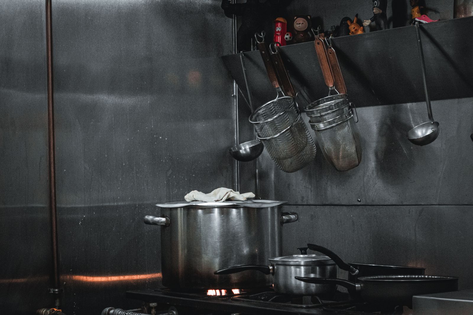 Placa de cocción, ollas y utensilios en una cocina profesional.